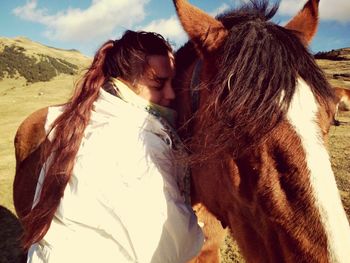 Young woman with horse standing against sky