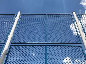 Low angle view of chainlink fence against blue sky