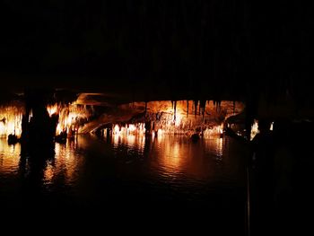 Illuminated river against sky at night