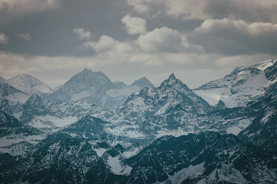 Scenic view of snowcapped mountains against cloudy sky