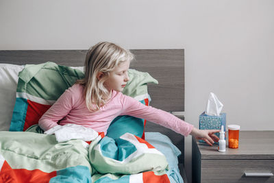 Full length of woman sitting on bed at home