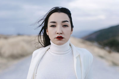 Portrait of beautiful young woman standing on land