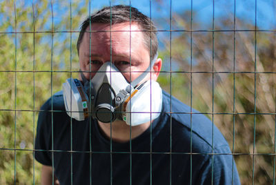 Portrait of man holding umbrella against fence