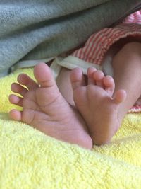 Low section of baby lying on bed