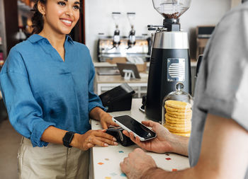 Midsection of customer making nfc payment at cafe