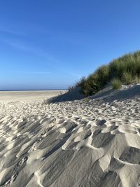 Scenic view of beach against clear blue sky