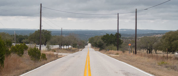 Road by trees against sky