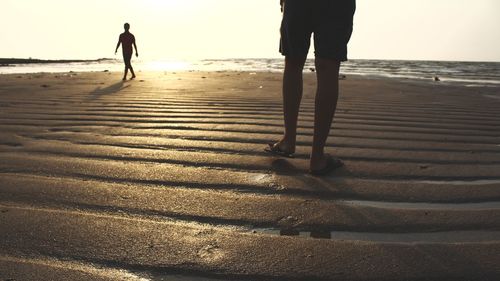 Silhouette people walking on beach during sunset