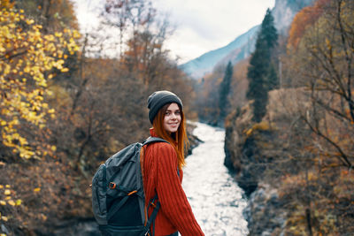 Young woman standing by trees during autumn