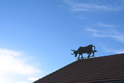 Low angle view of horse on roof against sky