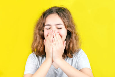 Portrait of teenage girl against yellow background