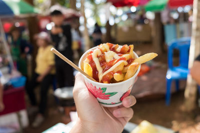 Close-up of hand holding french fries in bowl