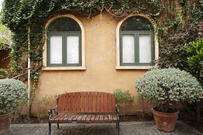 Potted plants on empty bench against building