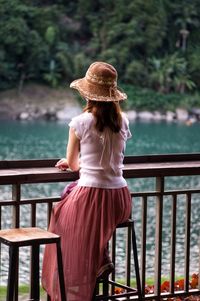 Side view of woman sitting on railing