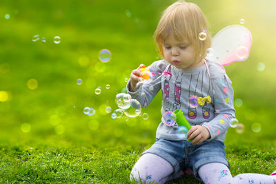 Full length of cute girl playing with bubbles