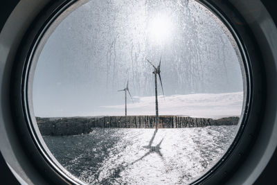 Scenic view of sky and wind turbines seen through glass window