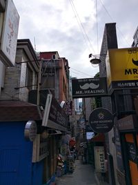 Road sign by buildings against sky in city