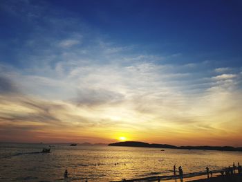 Silhouette people on beach against sky during sunset