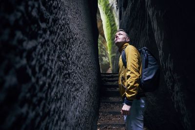 Side view of man standing amidst wall