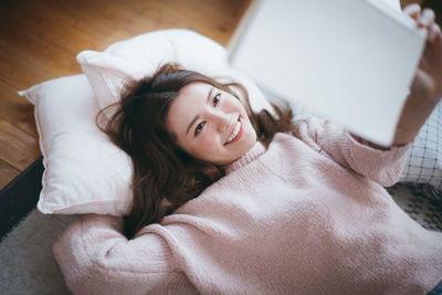 Smiling woman reading book on bed at home