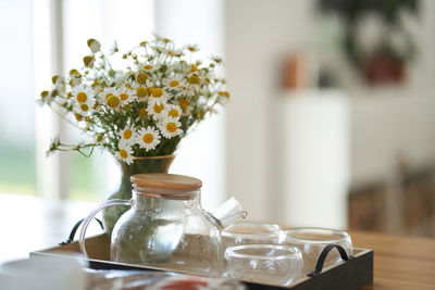 Close-up of vase with daisies on table