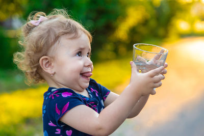 Cute girl holding drinking water at public park