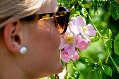 Close-up of young woman smelling pink flowers blooming on tree