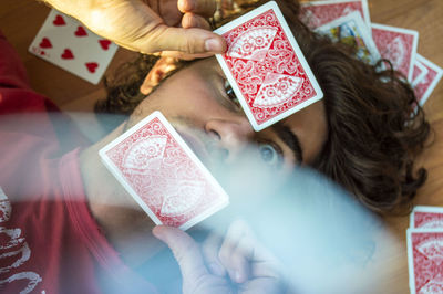 High angle view of man with playing cards lying on hardwood floor