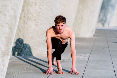 Portrait of shirtless man exercising in city