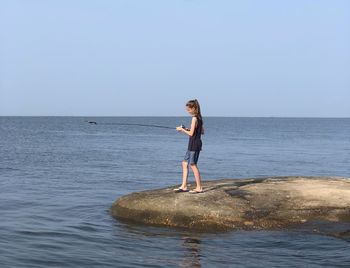 Young woman standing in sea against sky