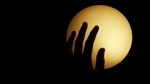 Cropped image of hand on illuminated light in darkroom