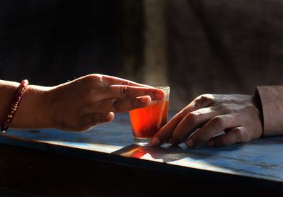 Close-up of hand holding drink on table