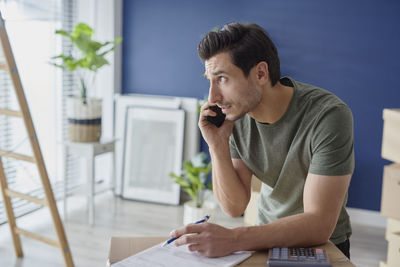 Young man using mobile phone while sitting on table