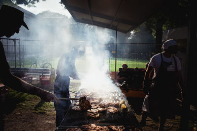 People grilling meat at barbeque grill