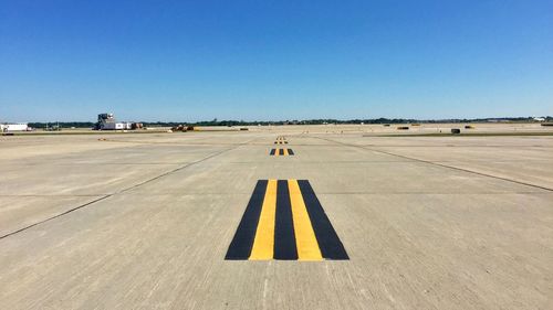 Airplane on airport runway against clear blue sky