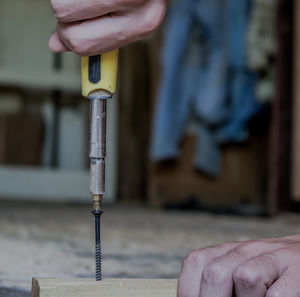 Cropped hands of person drilling in wood