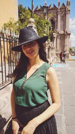 Portrait of smiling woman wearing hat in city