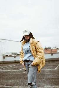 Young woman standing on road against the sky