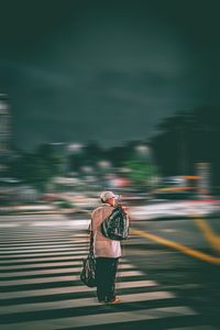 Rear view of woman walking on road in city