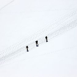 Silhouette people walking on snow covered landscape