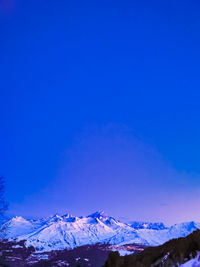 Scenic view of snowcapped mountains against blue sky