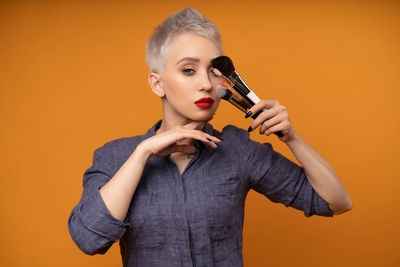 Portrait of a beautiful young woman against orange background