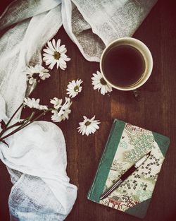 High angle view of pen on book by fabric and coffee cup on wooden table