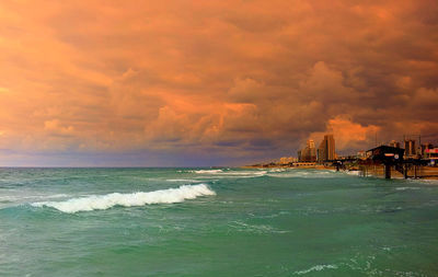 Scenic view of sea against cloudy sky during sunset