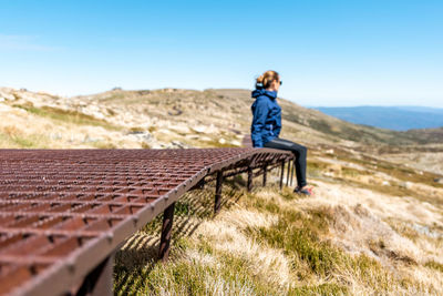 Full length of woman sitting against clear sky