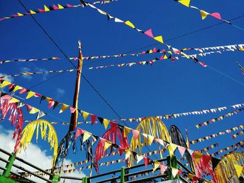 Low angle view of colorful flags hanging against clear blue sky