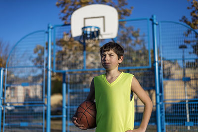 Portrait of teenage boy with ball in background