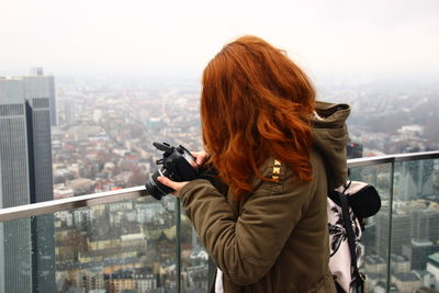 Rear view of woman photographing cityscape during winter