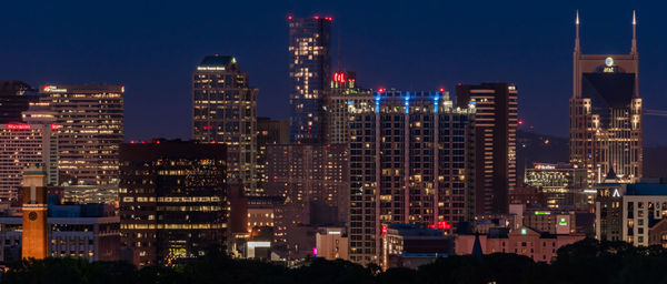 Illuminated buildings in city against sky at night