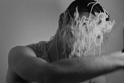 Close-up of young man with noodles covered face against wall